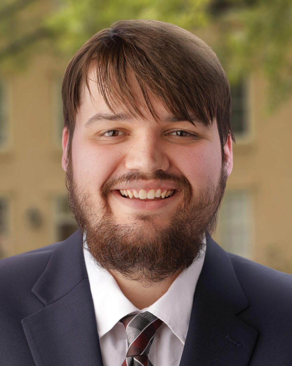 A young man in a suit and tie smiles at the camera